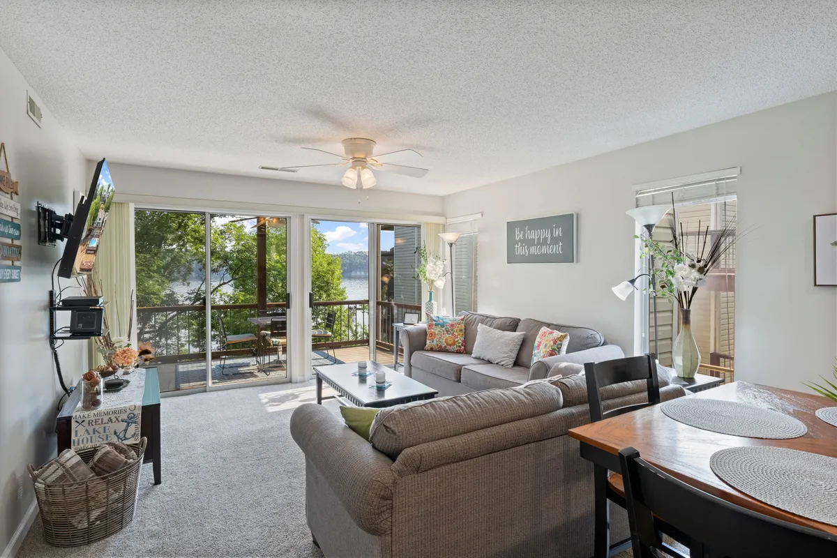 This image features a cheerful living area with a sofa and dining table, bathed in natural light that comes through large windows offering scenic views outside. The space evokes a sense of relaxation and connection to the outdoors, with the view hinting at the landscape beyond the home.