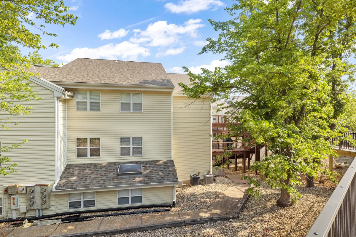 This image shows the exterior of the condo building framed by lush greenery and a spacious deck area, hinting at secluded relaxation spots and the inviting, calm environment the property offers.