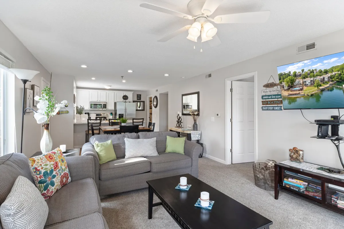 A cozy living room scene featuring a sofa with colorful pillows, a coffee table with candles, and a TV displaying a scenic view. The atmosphere is inviting and ideal for movie nights or quiet evenings at home, reinforcing the emphasis on comfort and togetherness.