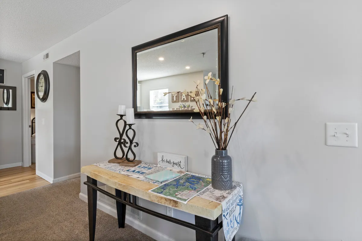 A bright entryway featuring a mirror, a stylish console table with a decorative vase, and a candlestick holder. This scene immediately communicates a sense of arrival, safety, and welcome, setting the tone for the sanctuary within.