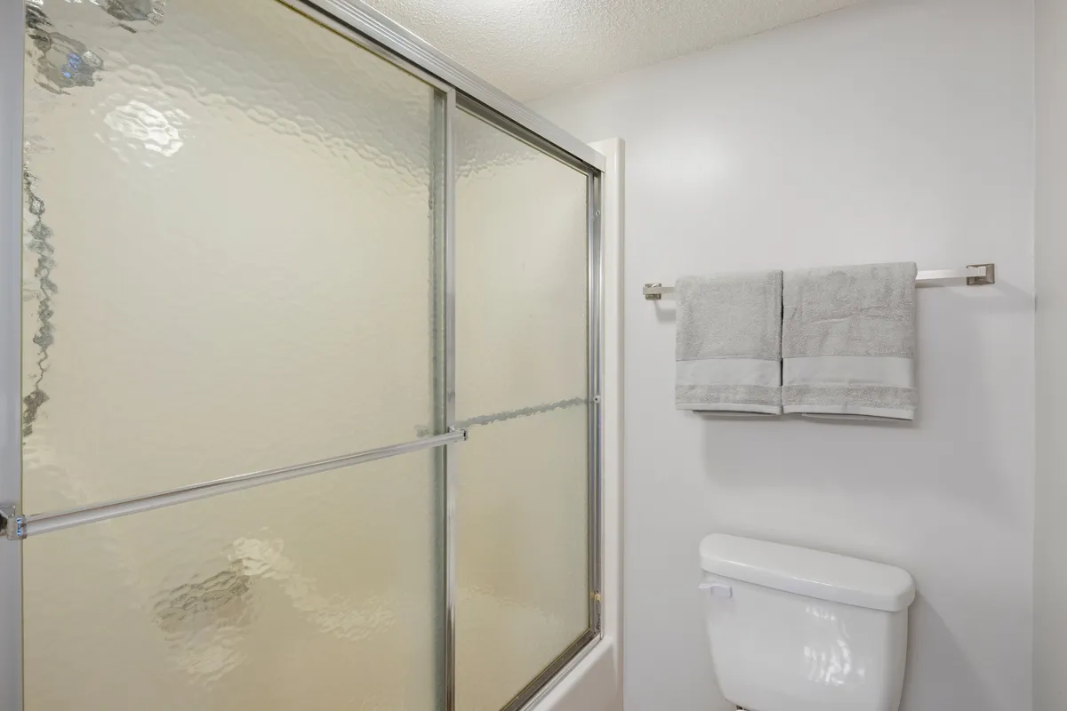 A tidy bathroom with a glass shower enclosure, fresh towels, and a clean, organized layout. The design is modern yet welcoming, ideal for relaxation and personal routines.